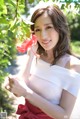 A young woman holding a red flower in her hand.