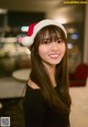 A woman wearing a santa hat smiles at the camera.