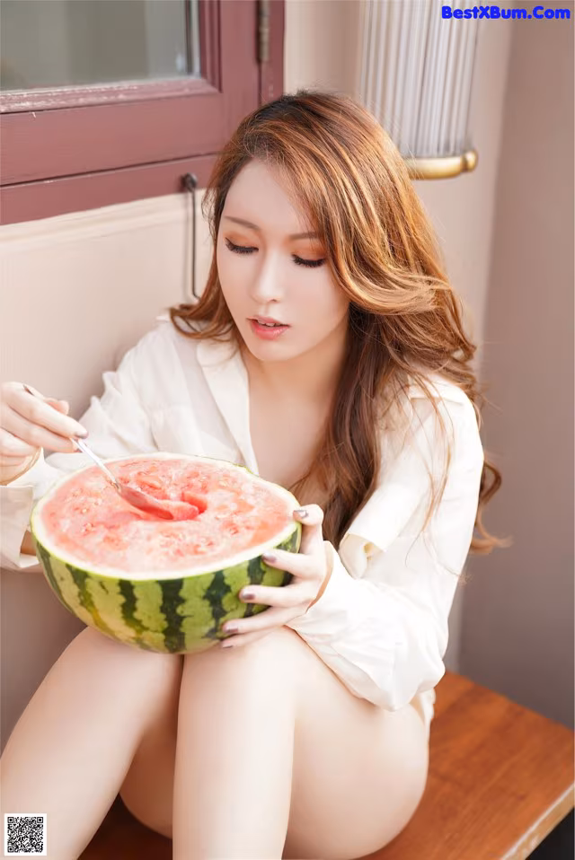A woman sitting on a bench eating a watermelon.