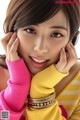 A woman in a yellow and pink sweater posing for a picture.