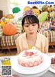 A woman sitting at a table with a birthday cake.