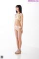 A woman in a bikini standing in front of a white wall.