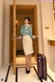 A woman standing in front of a door with a suitcase.