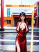 A woman in a red dress standing in front of a gas station.