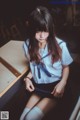 A woman in a school uniform sitting on a table.