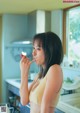 A woman in a yellow bikini eating a strawberry.