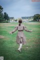 A woman in a trench coat is walking in the grass.