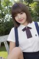 A young woman in a school uniform sitting on a bench.