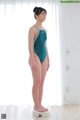 A woman in a green swimsuit standing on a scale.