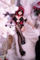 A woman in a red and black lingerie sitting on a white fur rug.