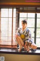 A woman in a kimono sitting on a window sill.