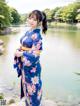 A woman in a blue kimono standing by a lake.